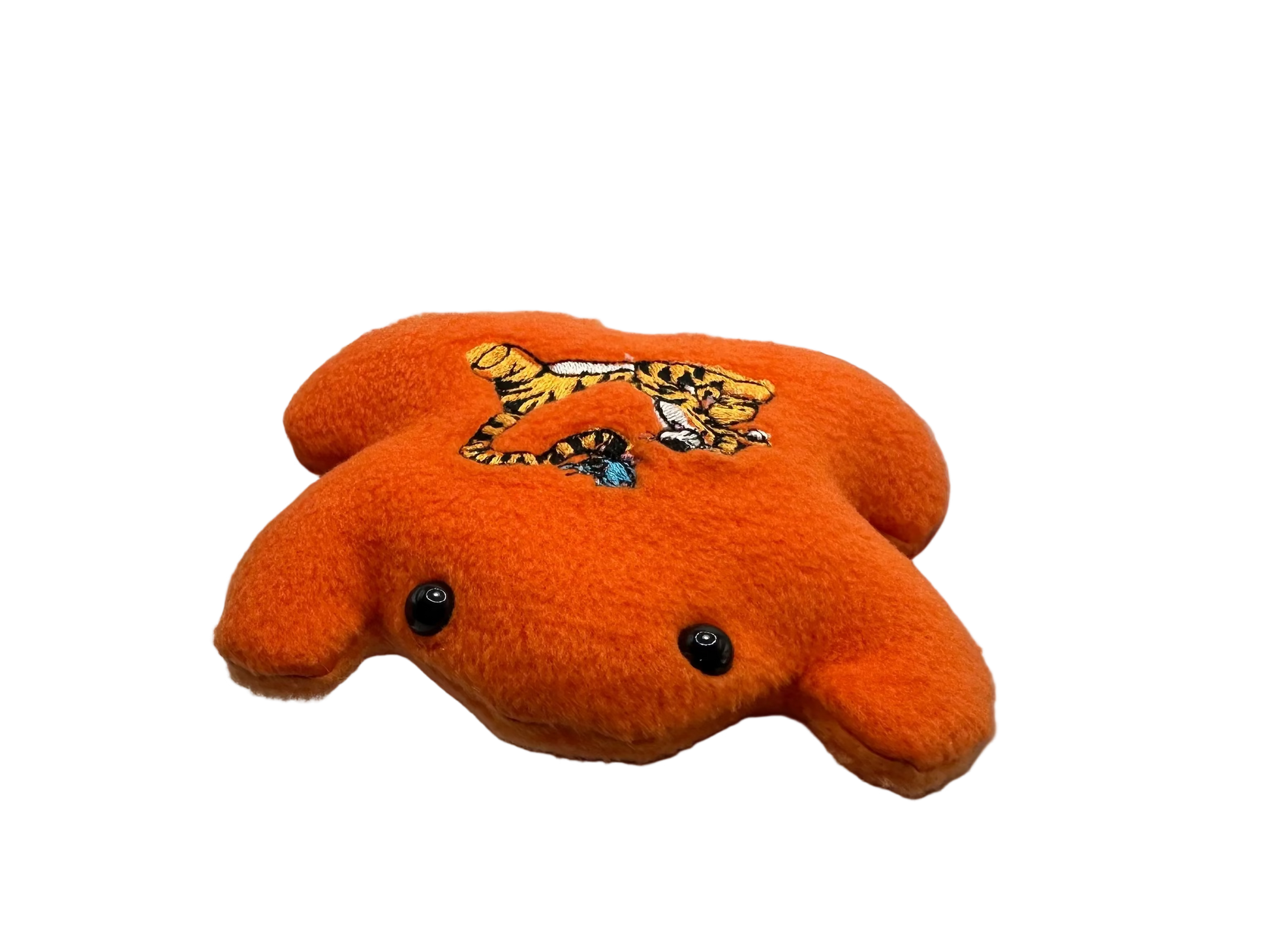 Orange plush toy with a tiger design held in a hand against a white background
