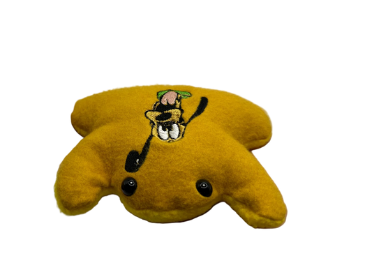 Yellow plush toy with a character design held in a hand against a white background
